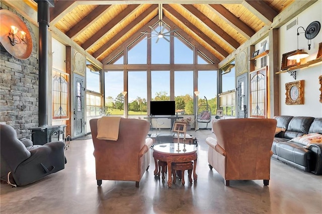 sunroom with lofted ceiling with beams, a wood stove, a wealth of natural light, and wooden ceiling