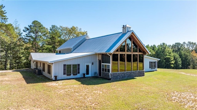 rear view of property with a sunroom, a lawn, and central AC unit