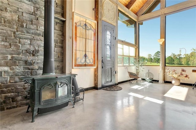 interior space with vaulted ceiling with beams, a wood stove, and wood ceiling