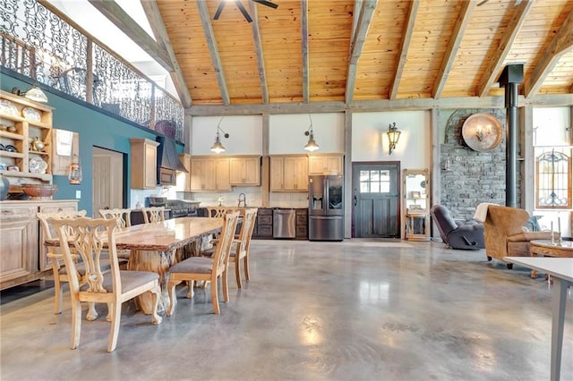 dining area featuring beamed ceiling, wood ceiling, concrete flooring, and high vaulted ceiling