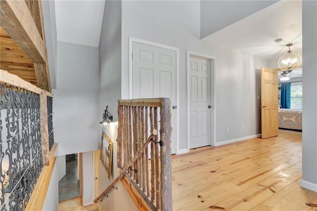 hallway featuring a chandelier, vaulted ceiling, and wood-type flooring