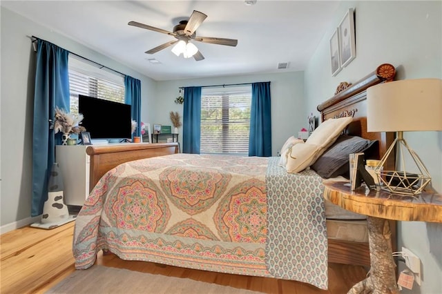 bedroom with multiple windows, hardwood / wood-style floors, and ceiling fan