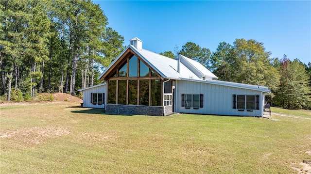 back of property with a sunroom and a lawn