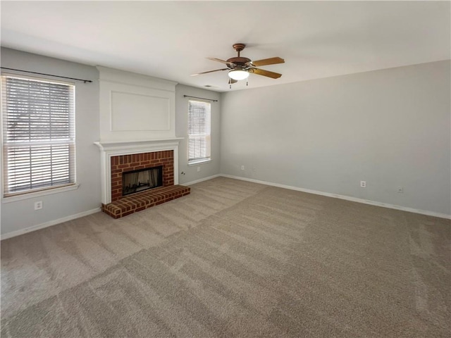 unfurnished living room featuring a ceiling fan, baseboards, light colored carpet, and a fireplace