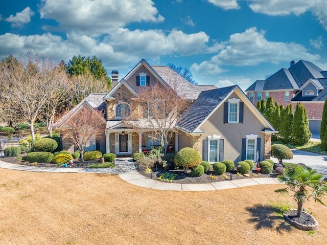 traditional home featuring stone siding, a chimney, a front lawn, and stucco siding