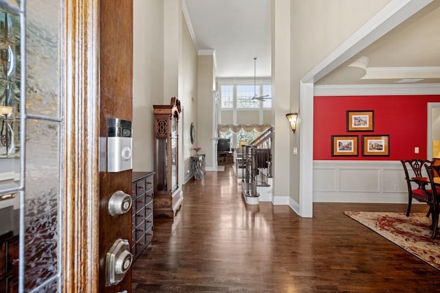 entryway with ornamental molding, stairway, dark wood finished floors, and a decorative wall