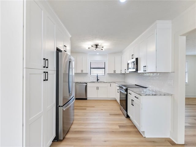 kitchen with white cabinetry, tasteful backsplash, light hardwood / wood-style flooring, appliances with stainless steel finishes, and light stone countertops