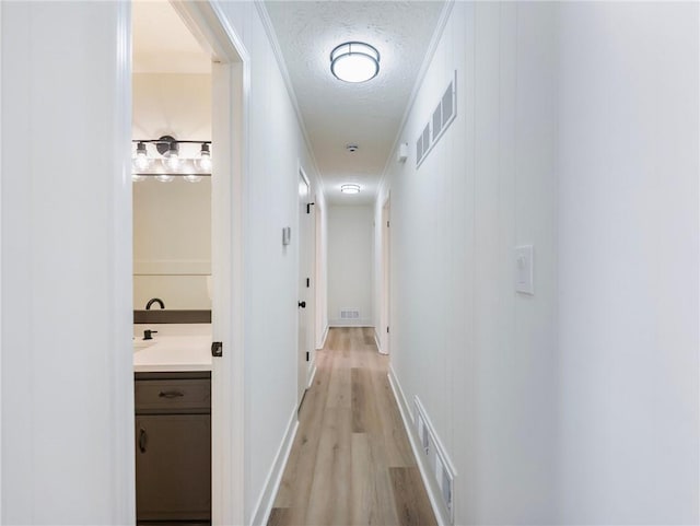 hallway with a textured ceiling and light hardwood / wood-style flooring