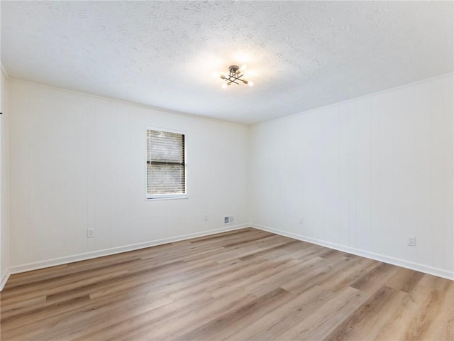 spare room with light hardwood / wood-style floors and a textured ceiling