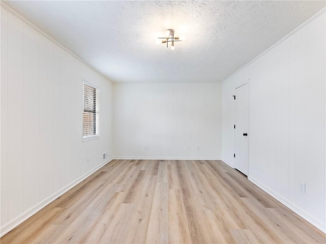 empty room with a textured ceiling and light hardwood / wood-style flooring