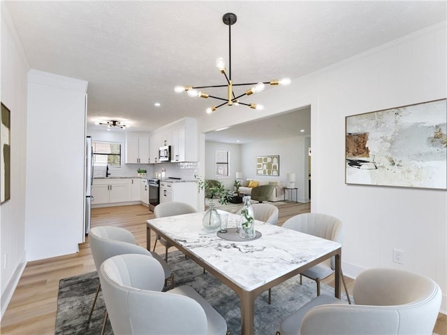 dining room with sink, an inviting chandelier, and light hardwood / wood-style flooring