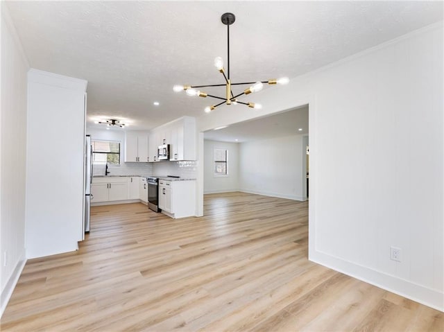 kitchen with appliances with stainless steel finishes, white cabinetry, an inviting chandelier, decorative light fixtures, and light wood-type flooring