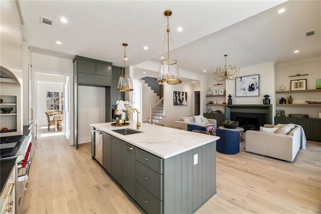 kitchen with sink, light hardwood / wood-style flooring, pendant lighting, light stone countertops, and a kitchen island with sink