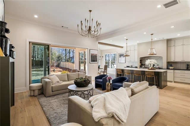 living room featuring ornamental molding, a notable chandelier, and light hardwood / wood-style floors