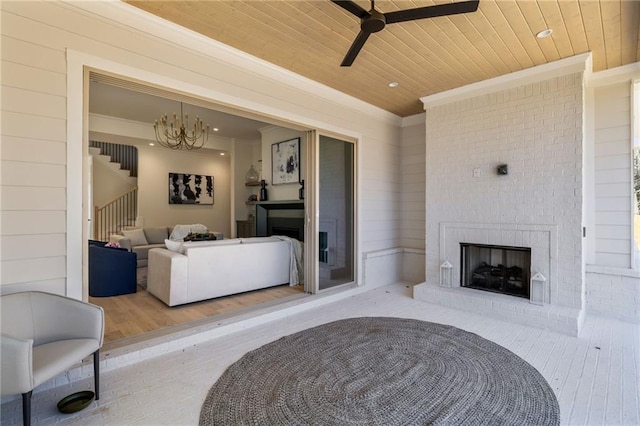 interior space featuring wood ceiling, crown molding, ceiling fan, a fireplace, and light hardwood / wood-style floors