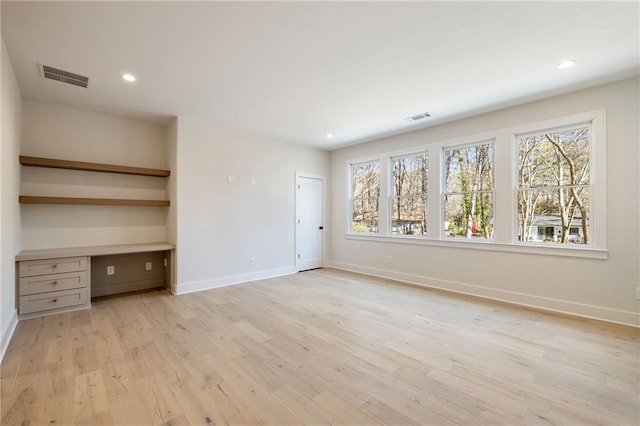 interior space with built in desk and light hardwood / wood-style floors