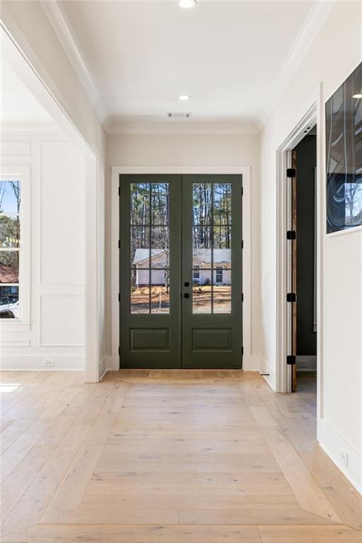 doorway featuring crown molding, light hardwood / wood-style flooring, and french doors