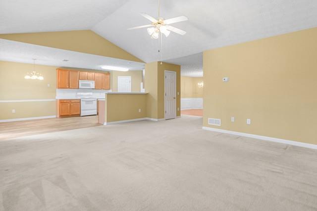 unfurnished living room featuring vaulted ceiling, light colored carpet, and ceiling fan with notable chandelier