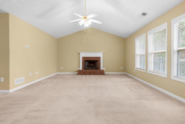 unfurnished living room featuring a fireplace, light colored carpet, vaulted ceiling, and ceiling fan