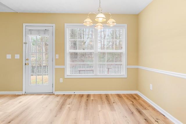 unfurnished dining area featuring wood-type flooring and an inviting chandelier