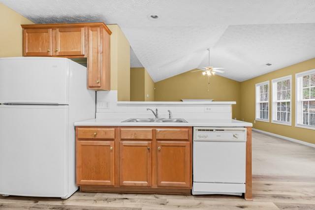 kitchen with white appliances, ceiling fan, sink, light hardwood / wood-style floors, and lofted ceiling