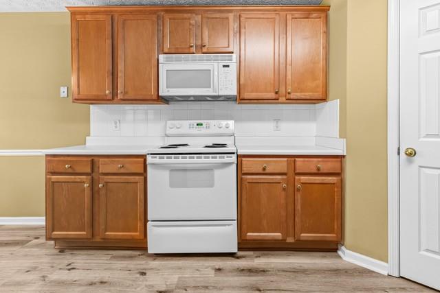 kitchen featuring backsplash, light hardwood / wood-style flooring, and white appliances