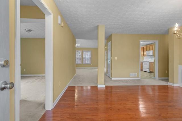 spare room with wood-type flooring, a textured ceiling, and a notable chandelier