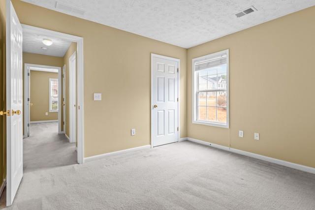 unfurnished bedroom featuring light carpet and a textured ceiling