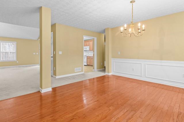 unfurnished room featuring hardwood / wood-style floors, a textured ceiling, and a notable chandelier