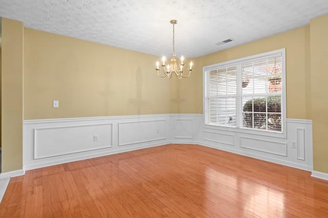 unfurnished room featuring hardwood / wood-style floors, a textured ceiling, and a notable chandelier