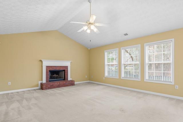 unfurnished living room featuring ceiling fan, lofted ceiling, a fireplace, and light carpet