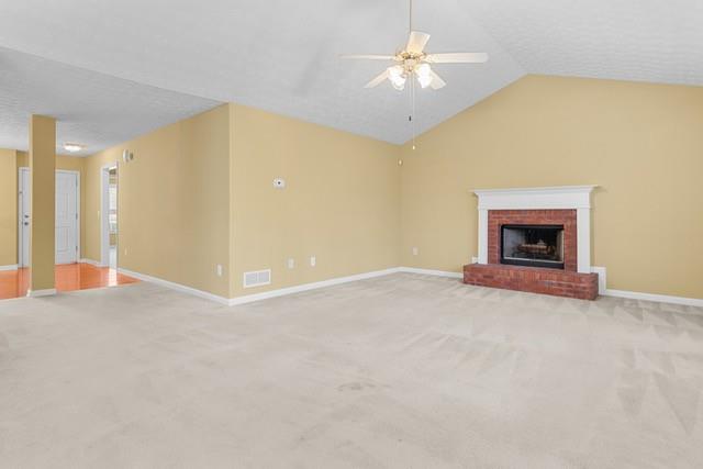 unfurnished living room with ceiling fan, a fireplace, light colored carpet, and lofted ceiling