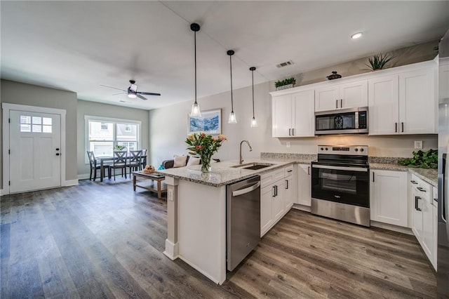 kitchen featuring white cabinets, dark wood-type flooring, stainless steel appliances, and decorative light fixtures