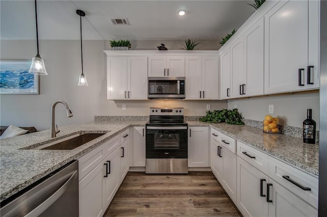 kitchen featuring pendant lighting, light stone countertops, stainless steel appliances, and dark hardwood / wood-style flooring