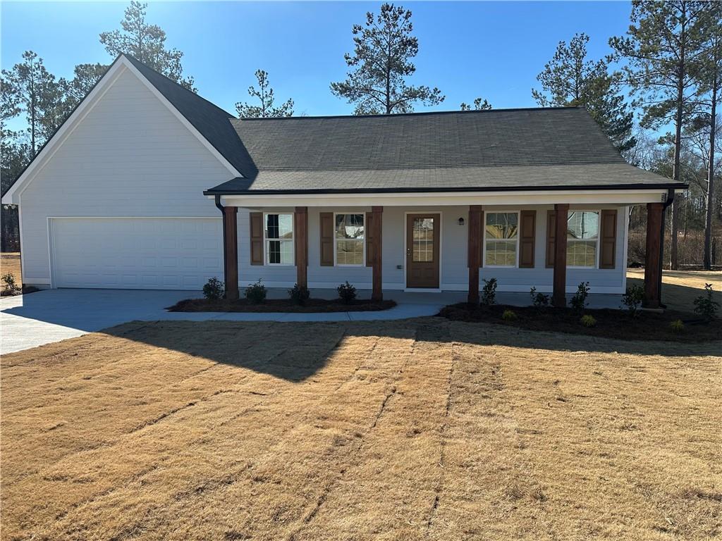 view of front facade featuring a porch, a garage, and a front yard