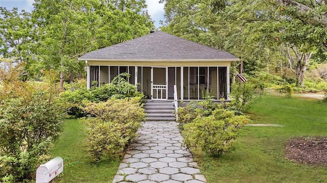 view of front of property with a shingled roof, a sunroom, and a front yard