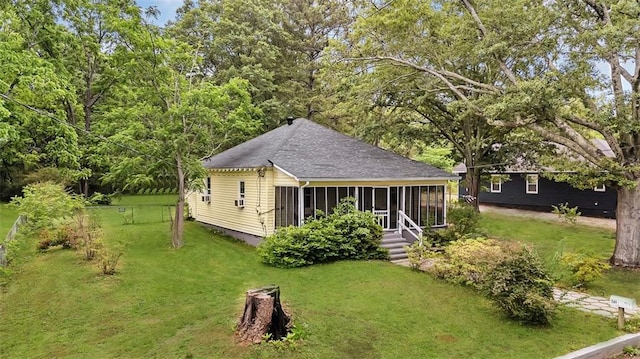 view of front of house with a sunroom, a front lawn, and a shingled roof
