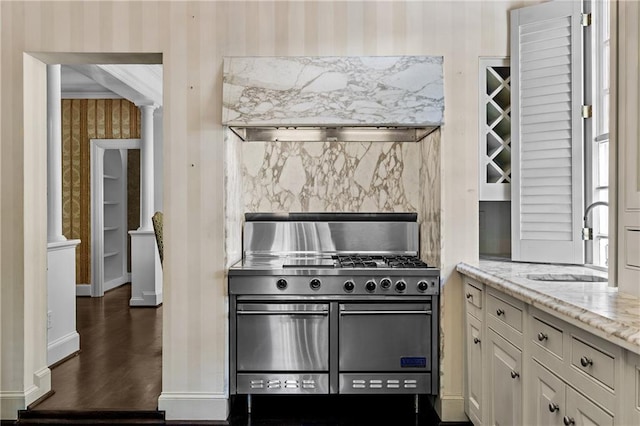 401 Peachtree Battle Ave NW, Atlanta, GA 30305 - kitchen featuring double oven range, wallpapered walls, a sink, light stone counters, and decorative columns