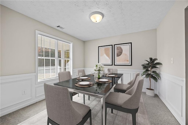 dining space with light colored carpet and a textured ceiling