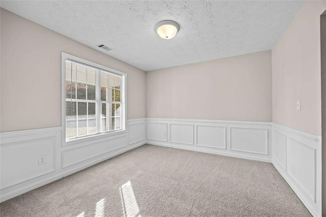 unfurnished room featuring light carpet and a textured ceiling