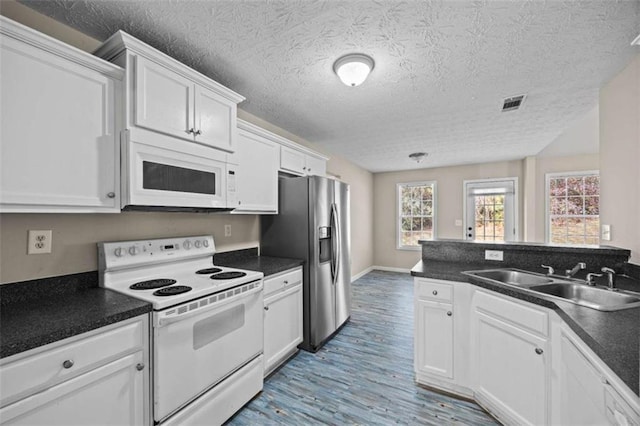 kitchen featuring sink, white cabinetry, a textured ceiling, white appliances, and light hardwood / wood-style floors