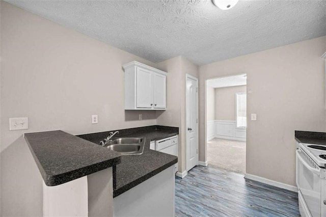 kitchen with sink, white appliances, white cabinetry, dark hardwood / wood-style floors, and kitchen peninsula