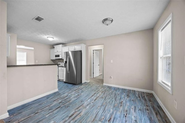 kitchen with white cabinets, kitchen peninsula, stainless steel refrigerator with ice dispenser, dark wood-type flooring, and a textured ceiling