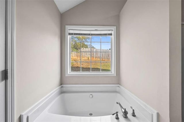 bathroom with lofted ceiling and a bathtub