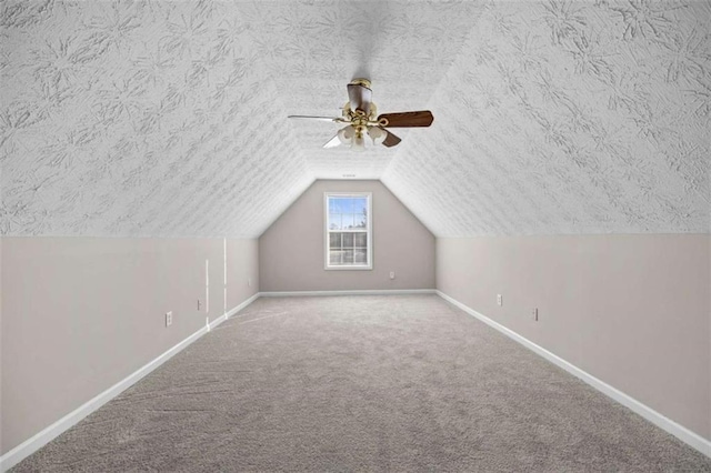 additional living space featuring lofted ceiling, carpet flooring, and a textured ceiling