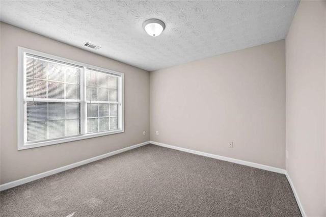 carpeted empty room featuring a textured ceiling