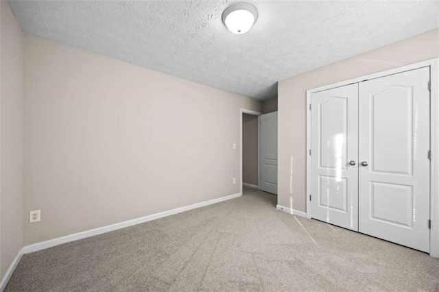 unfurnished bedroom featuring light carpet, a closet, and a textured ceiling