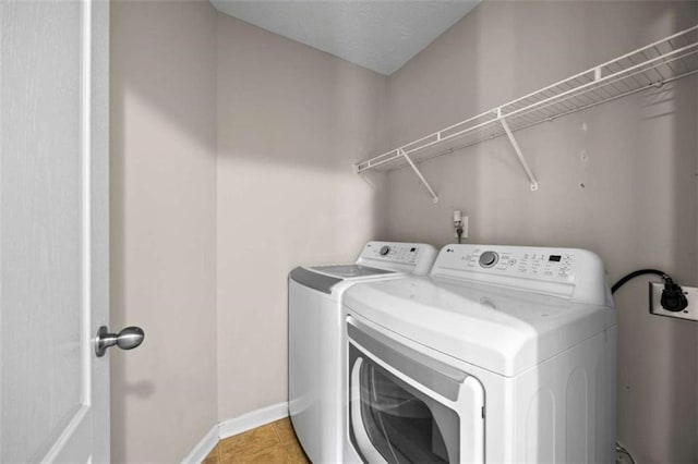 clothes washing area featuring washer and dryer and light tile patterned floors