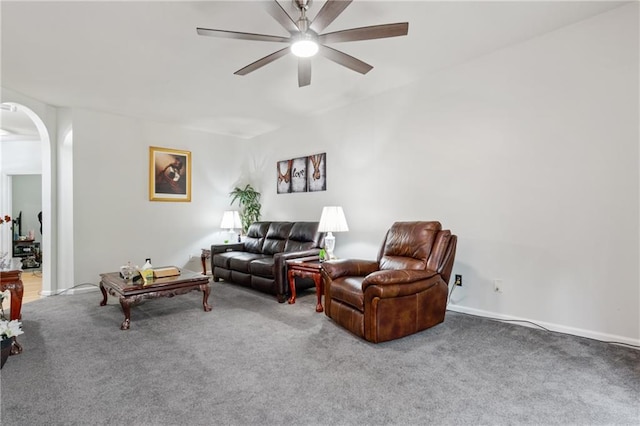 living area with arched walkways, baseboards, a ceiling fan, and carpet floors