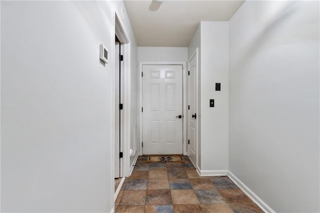 doorway to outside with baseboards and stone finish floor